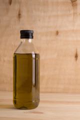 Olive oil in glass bottle on wooden background