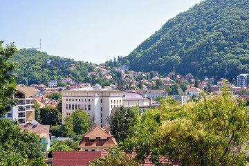 Obraz premium Daylight sunny view to city buildings and green mountains full of trees