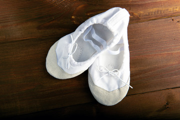 child's white dancing shoes on the wooden floor