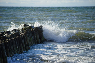 The sea wave with white small splashes beating about a coastal breakwater.