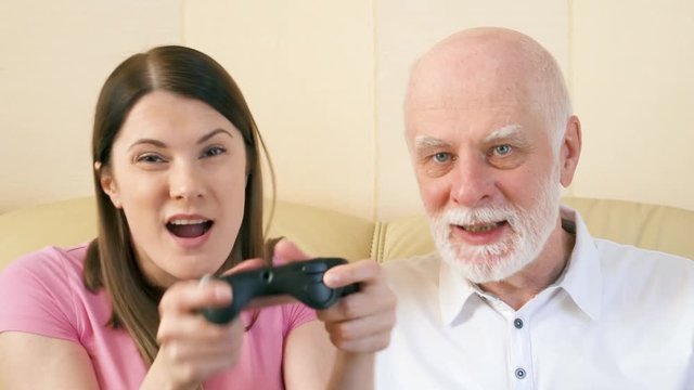 Father and daughter gamers playing video games at home. Addicted senior and teen players with remote controller of game console. Cybersport for active modern elderly people