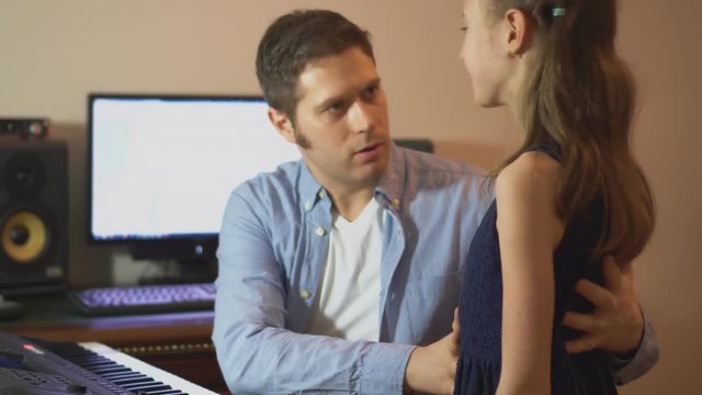 Male vocal coach teaching little girl how to sing. Focused on teacher.