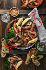 Paella pan with roasted tiger prawns and many dishes, bread and wine