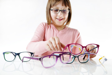 Dziewczynka trzyma kolorowe oprawki okularów.