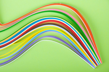 variety of colored paper stripes laying on green background