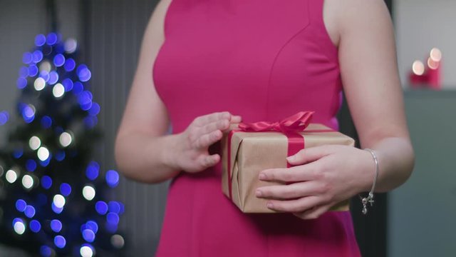 Closeup of a woman's hands holding and fumbling a Christmas gift or present. A happy wife concept. Soft focus