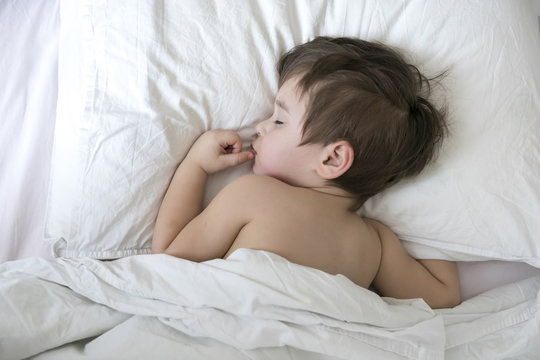 Sleeping little boy. Carefree sleep little baby with a soft toy on the bed. Close-up portrait of a beautiful sleeping child on knitted blanket. Sweet dreams. Good night. Healthy sleep. daytime sleep