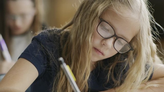Pan up to girl writing on test at desk in classroom / Provo, Utah, United States