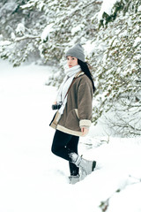 A beautiful girl walks through the snowy winter coniferous forest.