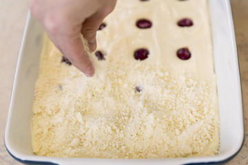 A woman is adding frozen cherries to a pie