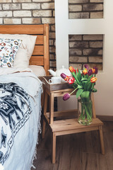 Colorful tulips in vase are in modern bedroom