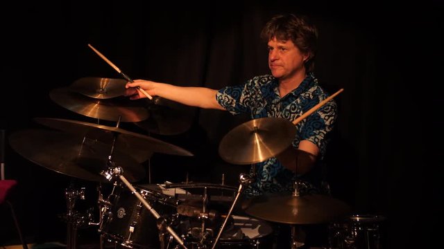 Drummer plays last seconds of a set and holds the cymbals.