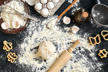 Cooking dough for cookies, butter, eggs, cooking equipment, flour on a black table. Top view with copy space, mockup for menu, recipe or culinary classes. Baking background.