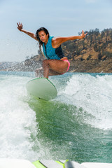 Fototapeta premium Mixed race fit young woman wakesurfing on a lake in California on a clear summer day