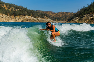 Mixed race fit young woman wakesurfing on a lake in California on a clear summer day - 192377822