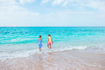 Happy little girls play with waves on the beach