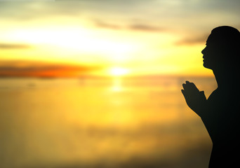 International women day concept: Silhouette woman pray at beach autumn sunrise background