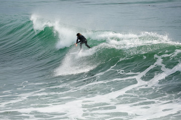 Surfer in California surfs large wave in beautiful blue water at beach