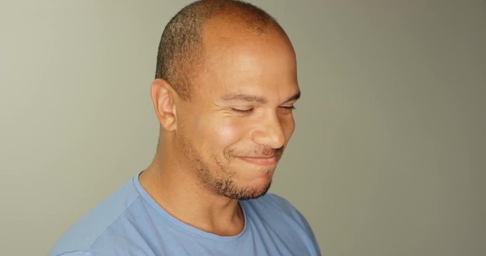 4K Close up portrait attractive mixed race man breaking into giggles in studio shot. Slow motion.