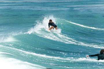 Young woman surfer flops down onto her board after missing a wave