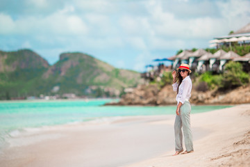 Young beautiful woman having fun on tropical seashore. Happy girl walking at white sand tropical beach