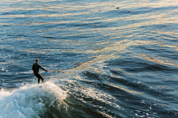 Overhead view of surfer on wave during a beautiful golden sunrise in California