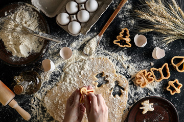 Close-up of a woman's hand with a dough. The woman is cutting a cookie with a cookie cutter in the...