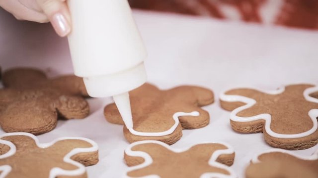 Decorating traditional gingerbread cookies with royal icing for Christmas