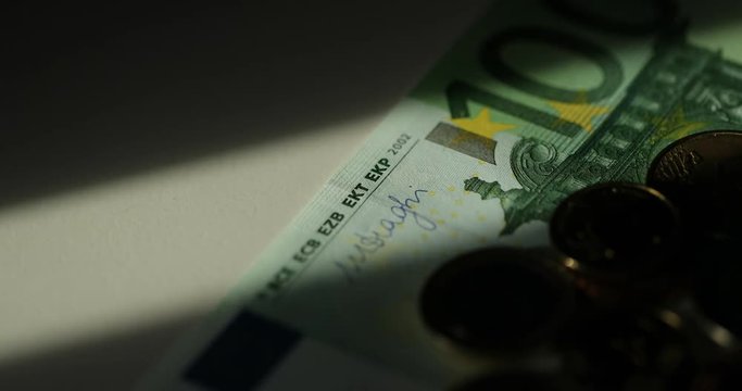 Seamless looping of a bunch of banknotes rotating on a plate with shallow depth of field. 100 Euro bills. Euro currency. Coins stacked on each other in different positions