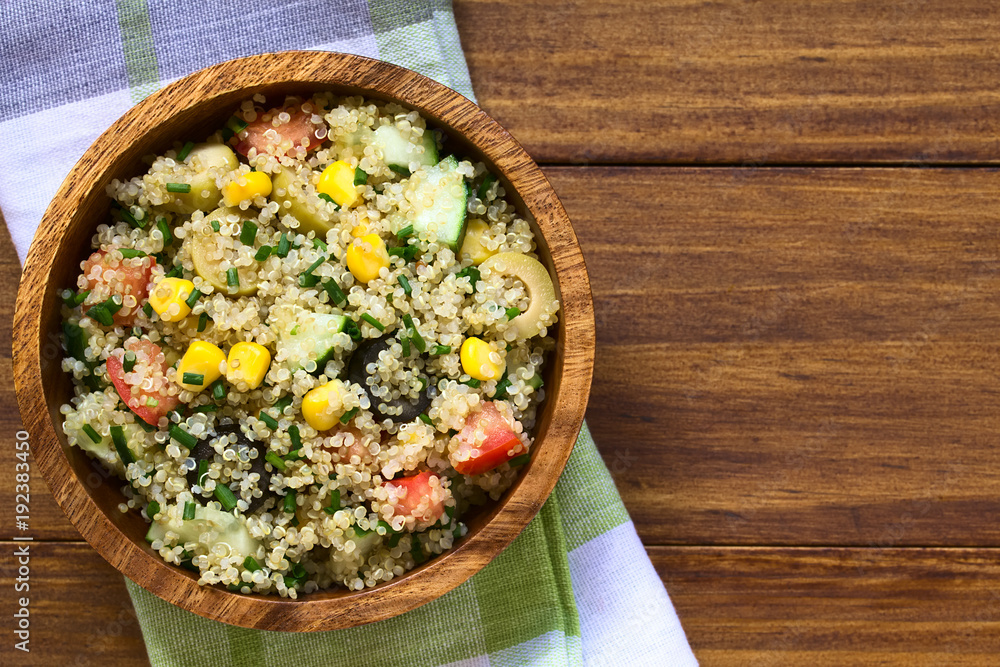 Poster Quinoa salad with sweet corn, olive, tomato, cucumber and chives in wooden bowl, photographed overhead on dark wood with natural light (Selective Focus, Focus on the top of the salad)