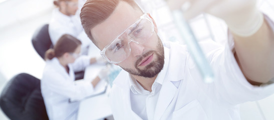 Fototapeta premium image is blurred. young scientist holding tube with the reagents