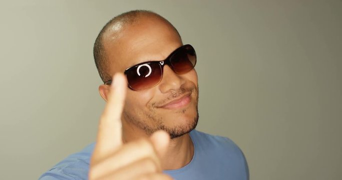 4K Laid back mixed race model moving gently to music in studio shot, wearing dark glasses with lighting reflected in the lenses. Slow motion.