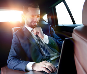 Fototapeta na wymiar businessman reads information on laptop while sitting in car