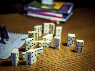domino pieces with books and pens on the table