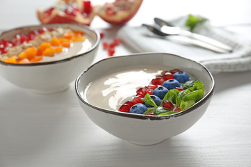 Yogurt with fruits in dishes on wooden table