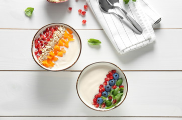 Yogurt with fruits in dishes on wooden table