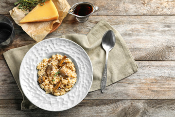 Plate with delicious risotto and mushrooms on wooden table