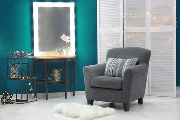 Stylish interior with trendy armchair near shaded spruce wall