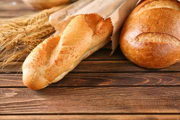 Different tasty bread on wooden table