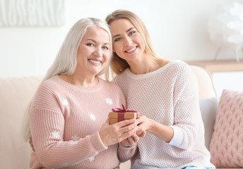 Young daughter and mother with gift box at home