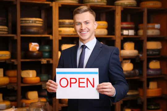 Business owner holding "OPEN" sign in his store