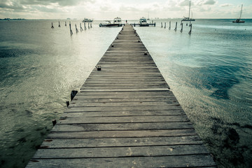 Outdoor view of a wooden dock into blue tropical sea in Isla Mujeres, Yucatan Mexico