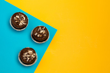 chocolate cupcakes on a color yellow-blue background decorated with chocolate shaving