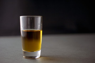glass of whiskey or cognac or alcohol drink, alcoholism and alcohol abuse concept, defocused, selective focus, close up, gray table, dark background