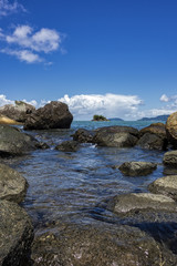 View of Juliao beach in Ilhabela - Sao Paulo, Brazil - with rocks in the sea on sunny day with blue sky with clouds