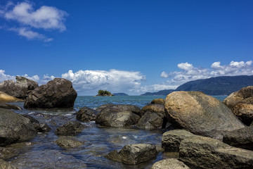 View of Juliao beach in Ilhabela - Sao Paulo, Brazil - with rocks in the sea on sunny day with blue sky with clouds