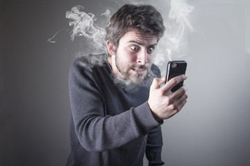 Young man insanely furious yelling at his phone, giving off steam and smoke