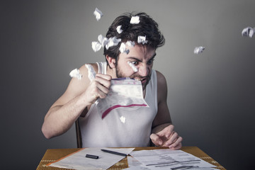 Angry young man tearing his bills, furious with the government and electricity companies