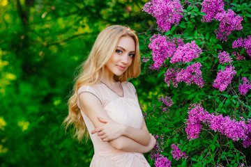charming beautiful blonde girl, portrait of girl surrounded by blooming flowers , beautiful smile, girl in spring garden
