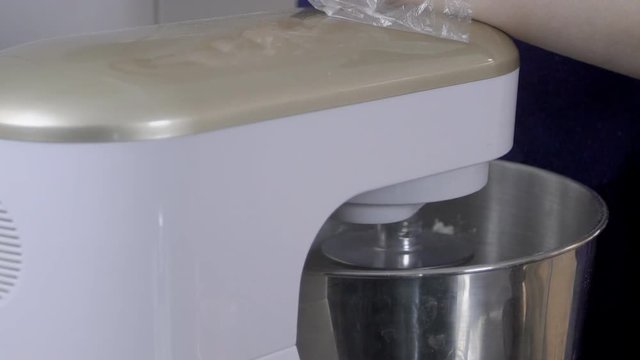 Close-up of process of kneading dough in the knead. White kitchen equipment is working on making a mixture for baking in automatic mode without human intervention. slowmotion slow motion